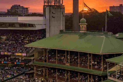 "Crowded cricket stadium with sunset sky in the background"
