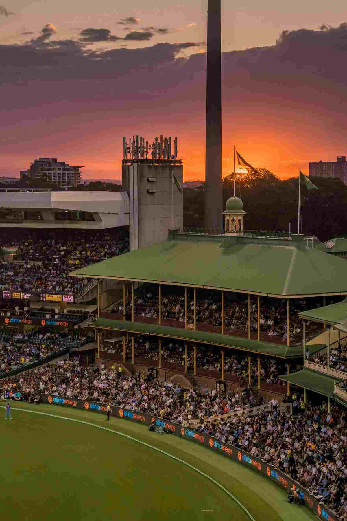 "Crowded cricket stadium with sunset sky in the background"