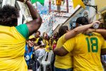 Crowd of Brazilian fans celebrating in the street wearing yellow jerseys during a festive event.