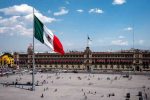 Mexican flag waving in Mexico City’s Zócalo square with the National Palace in the background.