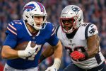 Quarterback from Buffalo in blue jersey running the ball as a New England defender closes in during a Patriots vs Bills football clash.