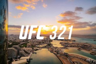 Aerial view of Abu Dhabi’s waterfront at sunset with bold white “UFC 321” text centered across the skyline.