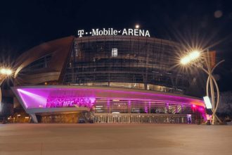 T-Mobile Arena illuminated at night with purple lights glowing across the entrance, home of UFC events in Las Vegas.
