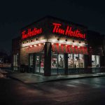 Tim Hortons coffee shop illuminated at night with glowing red signage.