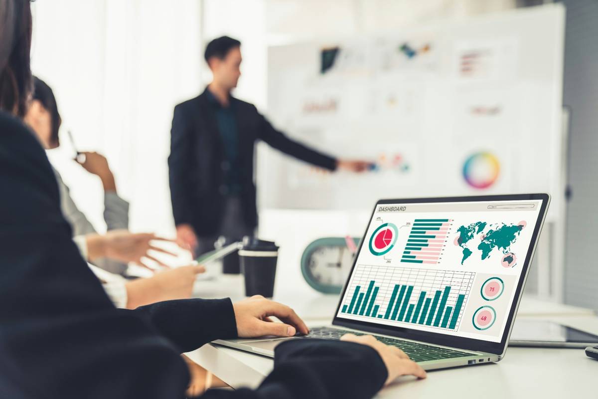 Professional team analyzing data charts on laptop dashboard during business meeting presentation.