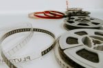 Film reels and strips of movie film laid out on a white surface, symbolizing cinema and storytelling.