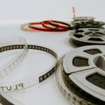 Film reels and strips of movie film laid out on a white surface, symbolizing cinema and storytelling.