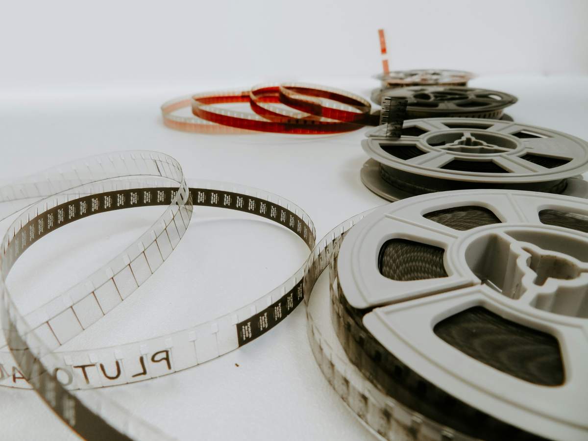 Film reels and strips of movie film laid out on a white surface, symbolizing cinema and storytelling.