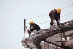 Construction workers welding and securing steel beams at a high-rise site.