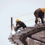 Construction workers welding and securing steel beams at a high-rise site.