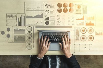 Business professional working on a laptop with financial graphs and data analytics visualizations.