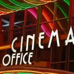 Colorful neon lights above a cinema box office entrance at night