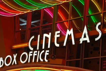 Colorful neon lights above a cinema box office entrance at night