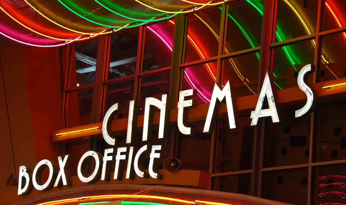 Colorful neon lights above a cinema box office entrance at night