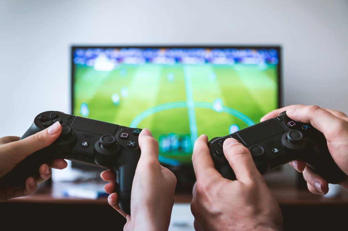 Two people holding game controllers while playing a football video game on TV.