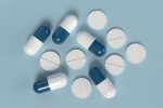 Blue and white capsules with round tablets on a light blue background representing modern pharmaceuticals.