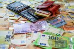 Wallets and euro banknotes spread across a table.