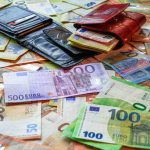Wallets and euro banknotes spread across a table.