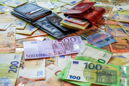 Wallets and euro banknotes spread across a table.